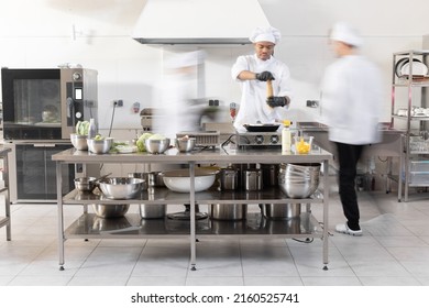 Chef cooks working in professional kitchen. Chefs hurry up, actively cooking meals for restaurant. Long exposure with motion blurred figures - Powered by Shutterstock