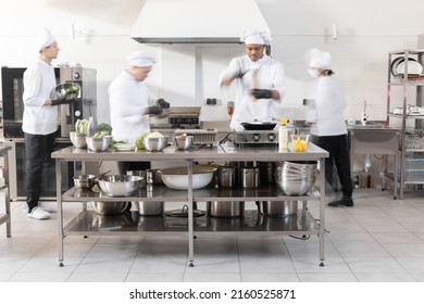 Chef cooks working in professional kitchen. Chefs hurry up, actively cooking meals for restaurant. Long exposure with motion blurred figures - Powered by Shutterstock