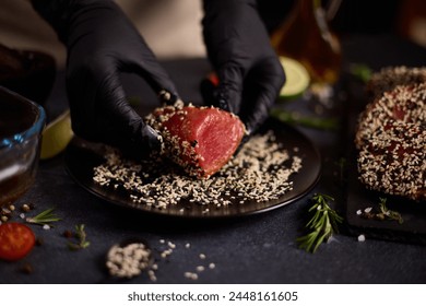 chef covers piece of tuna fillet with sesame seeds before cooking - Powered by Shutterstock