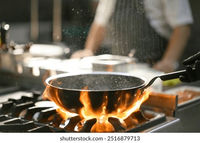 A chef creates a burst of flames while tossing food in a pan, displaying a dramatic cooking technique in the hotel's kitchen