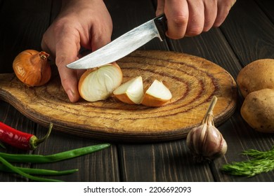 Chef Cuts Onion With A Knife On A Cutting Board For Making Soup For Lunch. Vegetable Diet Idea. Peasant Food.