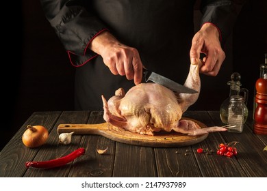 The Chef Cuts Raw Broiler Chicken Before Preparing Dinner. Work Environment On The Kitchen Table. Hotel Chicken Menu Idea.