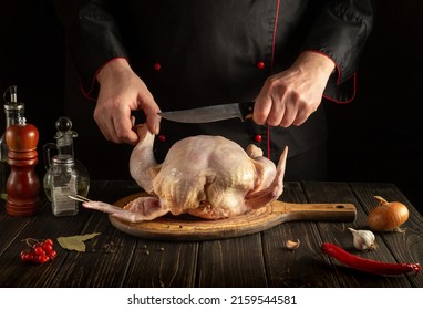 Chef Cuts Raw Broiler Chicken With A Knife. Cooking A National Dish In The Kitchen With Chicken.