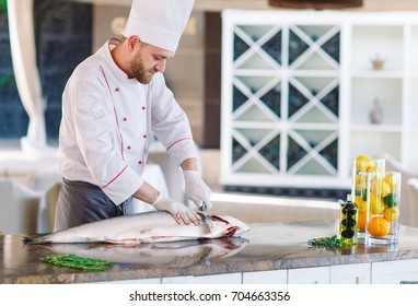 The chef cuts the salmon on the table.