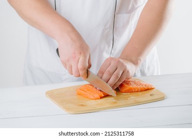 the chef cuts salmon on a wooden board, on a white background - Powered by Shutterstock