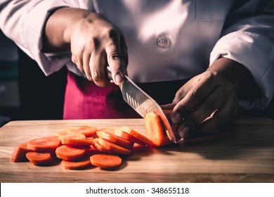 Chef cutting carrot on a wooden board - Powered by Shutterstock