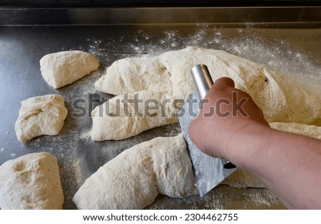 Chef Cutting Ciabatta dough on a metal table using a bench scrape Side view Foto stock © 