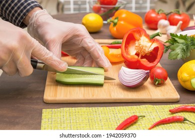 Chef cutting cucumber and vegetables for salad close up. Hands in gloves cooking healthy vegetarian vegan diet food