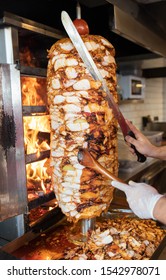 Koch Schneiden mit Doner-Messer Traditionelles türkisches Doner Kebab Fleisch. Shawarma oder Kreisel. Türkisches, griechisches oder mittelöstliches arab-arab-Stiel-Huhn Doner Kebab-Essen auf isoliertem Weiß.