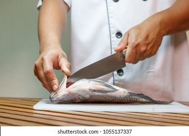 Chef Cutting Fish In The Kitchen.