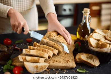 chef cutting Fresh bread on wooden cutting board on kitchen table - Powered by Shutterstock