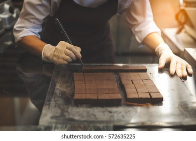 Chef Cutting Homemade Chocolate In Kitchen.