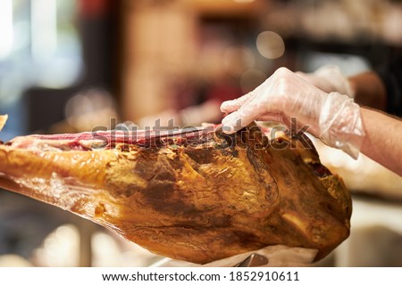 The chef is cutting the jamon. image of a ham cutter with a knife cutting a thin slice of ham. Dry Spanish ham, Jamon Serrano, Bellota, Italian Prosciutto Crudo or Parma ham.