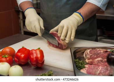 Chef Cutting Meat On Steaks With Knife