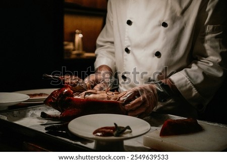Chef cutting and serving roasted Beijing duck in luxury restaurant of Beijing, China. This is a traditional dish since the imperial era; the duck skin is crispy and caramelized.
