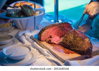 A Chef Cutting Steak At A Wedding Party With Tasty Sauces And Meals Around It