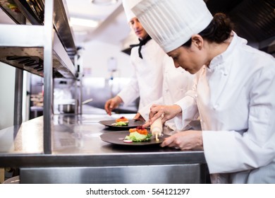 Chef decorating a food plate in the commercial kitchen - Powered by Shutterstock