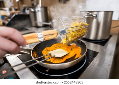 A chef drains pasta using a metal strainer while sautéing in a pan. Steam rises, showcasing a busy kitchen environment. The focus is on culinary skill and delicious food preparation. - Powered by Shutterstock