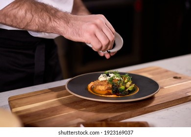 chef dressing salad with greens, adding some ingredients, chef adding finishing touch on dish before it goes on table. - Powered by Shutterstock