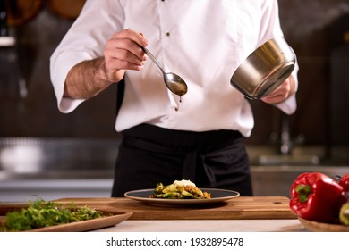 Chef Dressing Salad With Sauce, Pouring Sauce Into Plate, Finishing Cooking Of Meal In Restaurant Kitchen, Cropped Man In Apron At Work