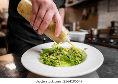 A chef drizzles a flavorful dressing over a fresh green salad in a stylish kitchen. The dish showcases vibrant greens, emphasizing freshness and culinary expertise. Perfect for food-related content. - Powered by Shutterstock