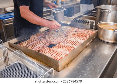 A chef expertly grills strips of meat bacon on a large griddle in a professional kitchen. The scene showcases culinary skills and the sizzling, smoky process of cooking crispy bacon. - Powered by Shutterstock