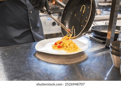 A chef expertly serves a freshly cooked pasta dish with tomatoes in a commercial kitchen setting. The image captures the art of cooking and the elegance of culinary presentation. - Powered by Shutterstock