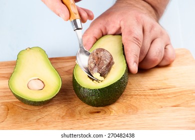 Chef extracts the bone of avocado with a spoon closeup