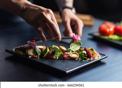 Chef finishing her plate and almost ready to serve at the table. Only hands. Finally dish dressing - Shutterstock ID 666234361