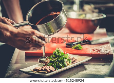 Chef finishing her plate and almost ready to serve at the table. Only hands. Finally dish dressing: steak meat with green salad