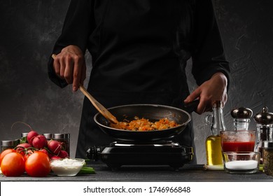 Chef fries vegetables in a pan, carrots and onions. Against the background of vegetables. Cooking and gastronomy. Home recipe book. - Shutterstock ID 1746966848