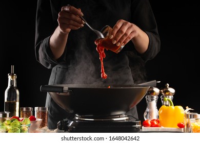 Chef fry meat in a pan, saturating tomato sauce, freezing in motion. Against the background of vegetables. Culinary recipes, delicious food. - Powered by Shutterstock