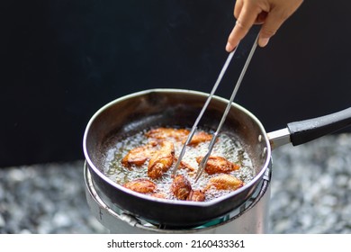 Chef is frying chicken wings in a pan location on gas stove Using vegetable oil made from natural soybeans. the oil is boiling The chef is flipping the chicken wings back and forth to make them cooked - Powered by Shutterstock