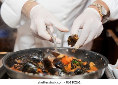 Chef frying mussels on commercial kitchen in restaurant, close-up on hands - Powered by Shutterstock