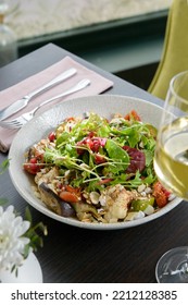 Chef Gourmet Bowl Of Salads, Beans, Carrot, Cauliflower, Eggplant, Nuts, Seeds And Herbs. Black Modern Restaurant Table. Side View