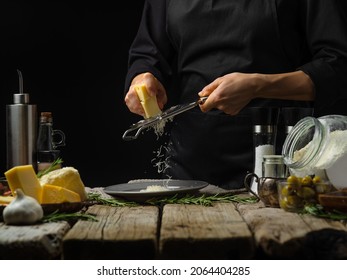 The chef grated cheese. Many ingredients for making pasta, pizza, focaccia, pie. Black background. Wooden texture. Bakery, pizzeria, restaurant, cooking blog, home cooking. - Powered by Shutterstock