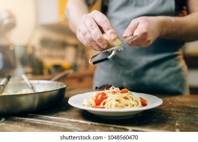 Chef grates cheese to the plate with fresh pasta