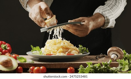 Chef grates hard cheese on top of a freshly prepared pasta dish, Pasta is mediterranean Italian traditional cuisine. - Powered by Shutterstock