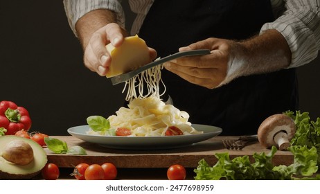 Chef grates hard cheese on top of a freshly prepared pasta dish, Pasta is mediterranean Italian traditional cuisine. - Powered by Shutterstock