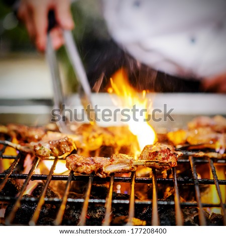 chef grilling lamb ribs on flame