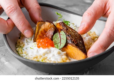 chef hand cooking grilled salmon fish fillet with creamy ptitim, cheese and caviar - Shutterstock ID 2255012135