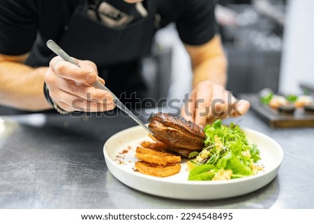 chef hand cooking Roasted Duck breast fillets with vegetable salad and batat in plate on restaurant kitchen