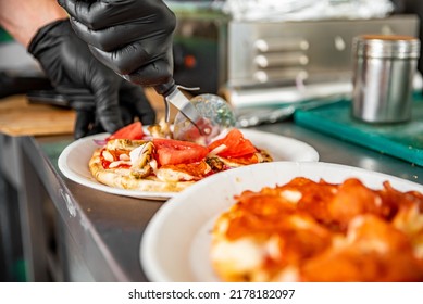 Chef Hand With Cutter Cutting Mini Pita Pizza To Pieces At Pizzeria Kitchen