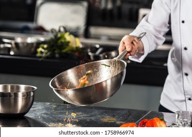 Chef Hand Keep Wok. Closeup Hands Tossing Food At Professional Kitchen. Chef In Uniform Prepare Asian Food.