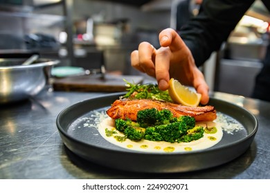 chef hand preparing a gourmet salmon steak with broccoli on restaurant kitchen - Powered by Shutterstock