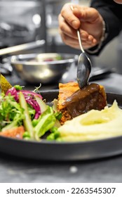 chef hand preparing Meat Pie with mashed potato and salad on restaurant kitchen