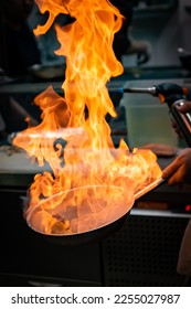 Chef hand in restaurant kitchen with pan, cooking flambe on food - Shutterstock ID 2255027987
