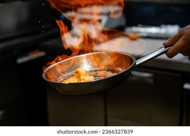 Chef hand in restaurant kitchen with pan, cooking flambe on shrimps - Powered by Shutterstock