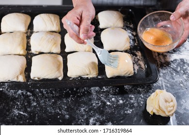 Chef hand smearing samsa pasties with egg yolk before putting the pasties in the oven at home. Stay and cooking at home. Quarantine. Isolation. Homemade. Uzbek cuisine.