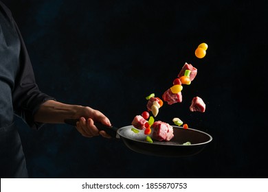 Chef hand tossed chopped pork with mix of vegetables above frying pan on black background. Backstage of cooking grilled meat for dinner. Food concept. Frozen motion. Asian cuisine. Close-up view. - Powered by Shutterstock